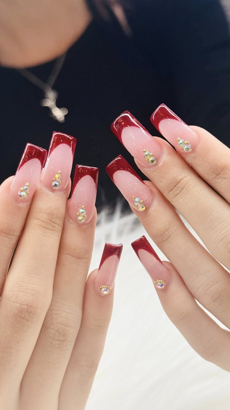 Deep red French tip nails with crystal accents
